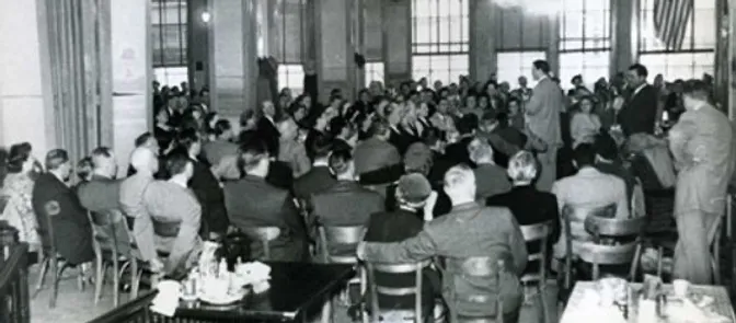 A group of men sitting in a room listening to a speaker